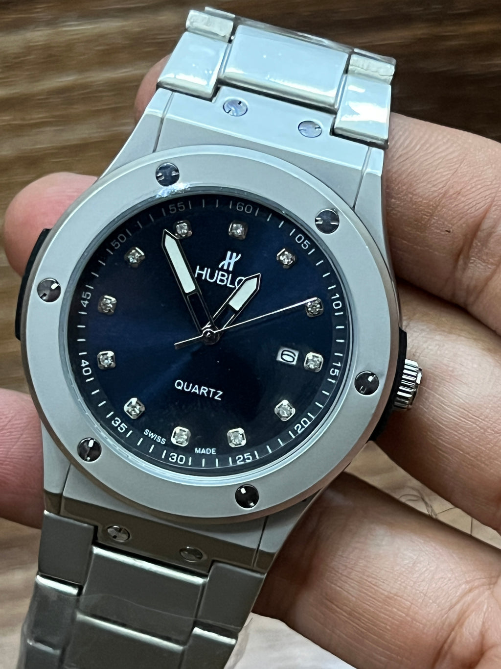 Silver Hublot watch with blue dial held in a hand