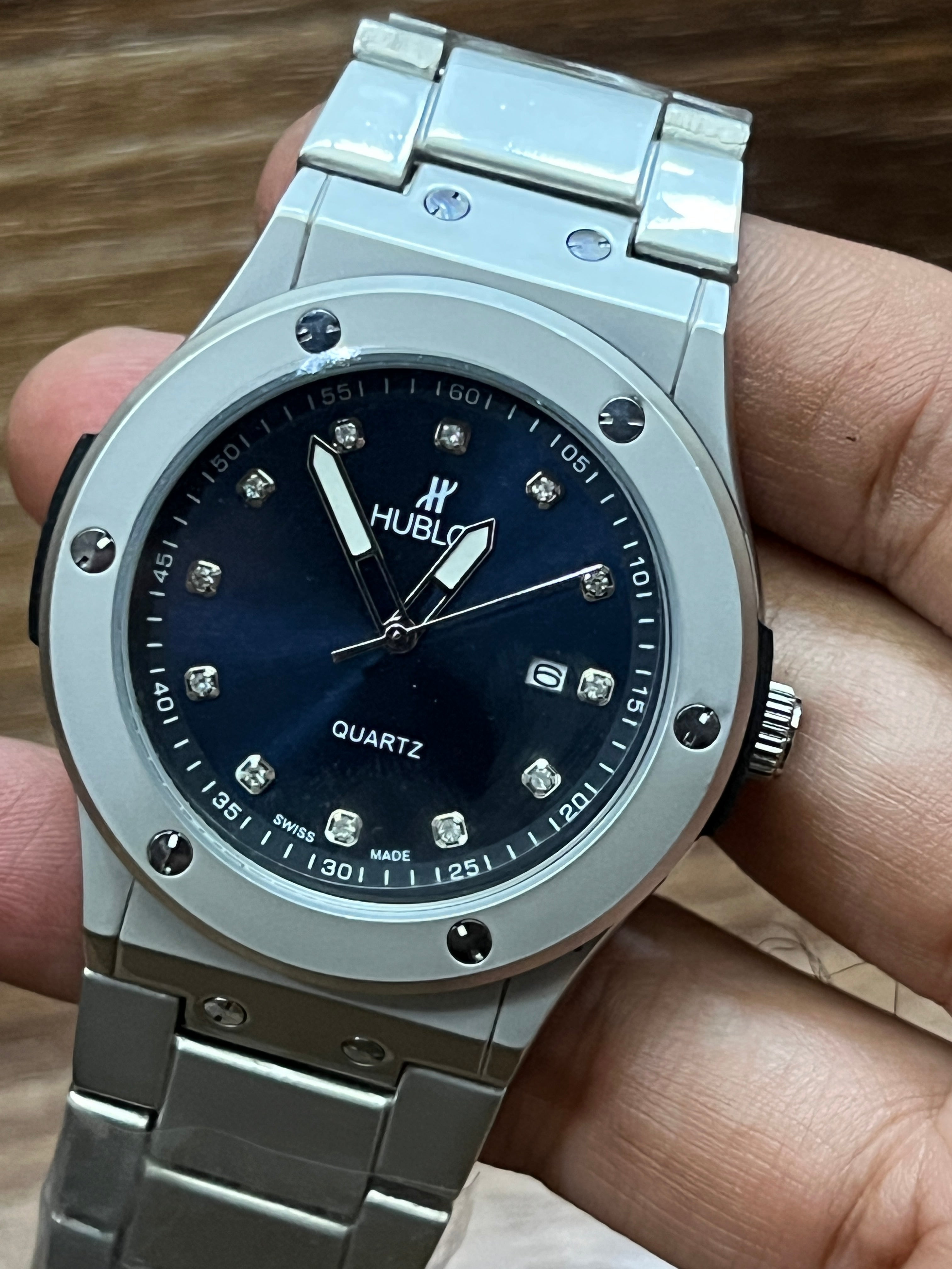 Silver Hublot watch with blue dial held in a hand