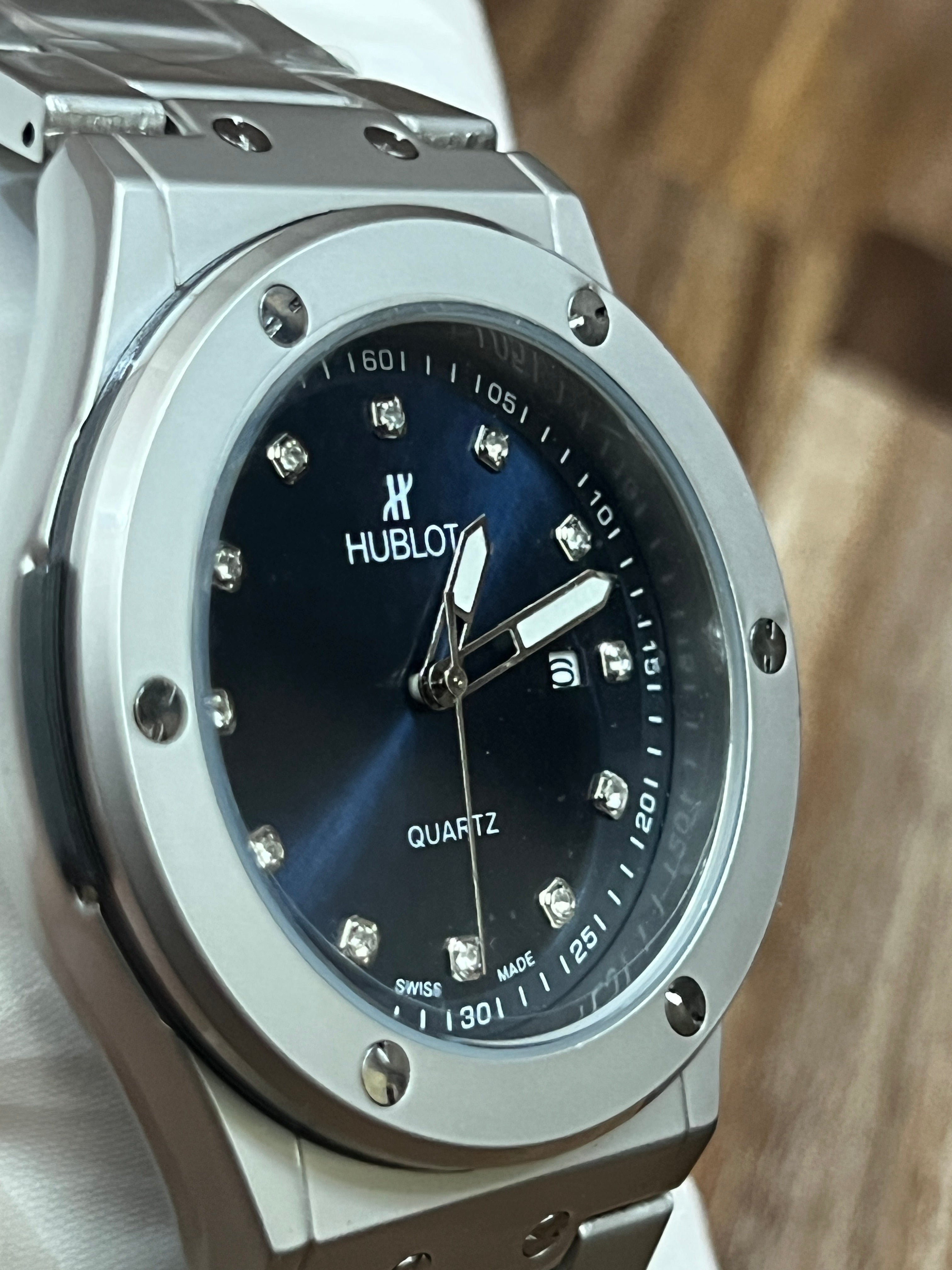 Hublot watch with blue dial and silver case on a wooden surface